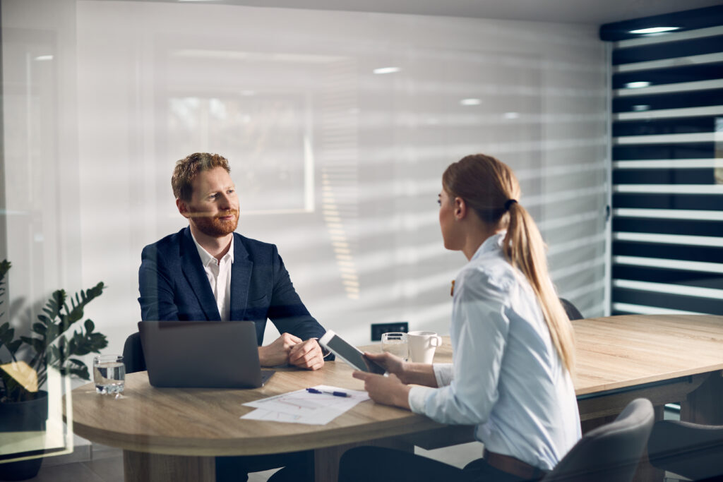 Two business professionals having a discussion at a modern office table, representing collaboration and planning for a joint venture